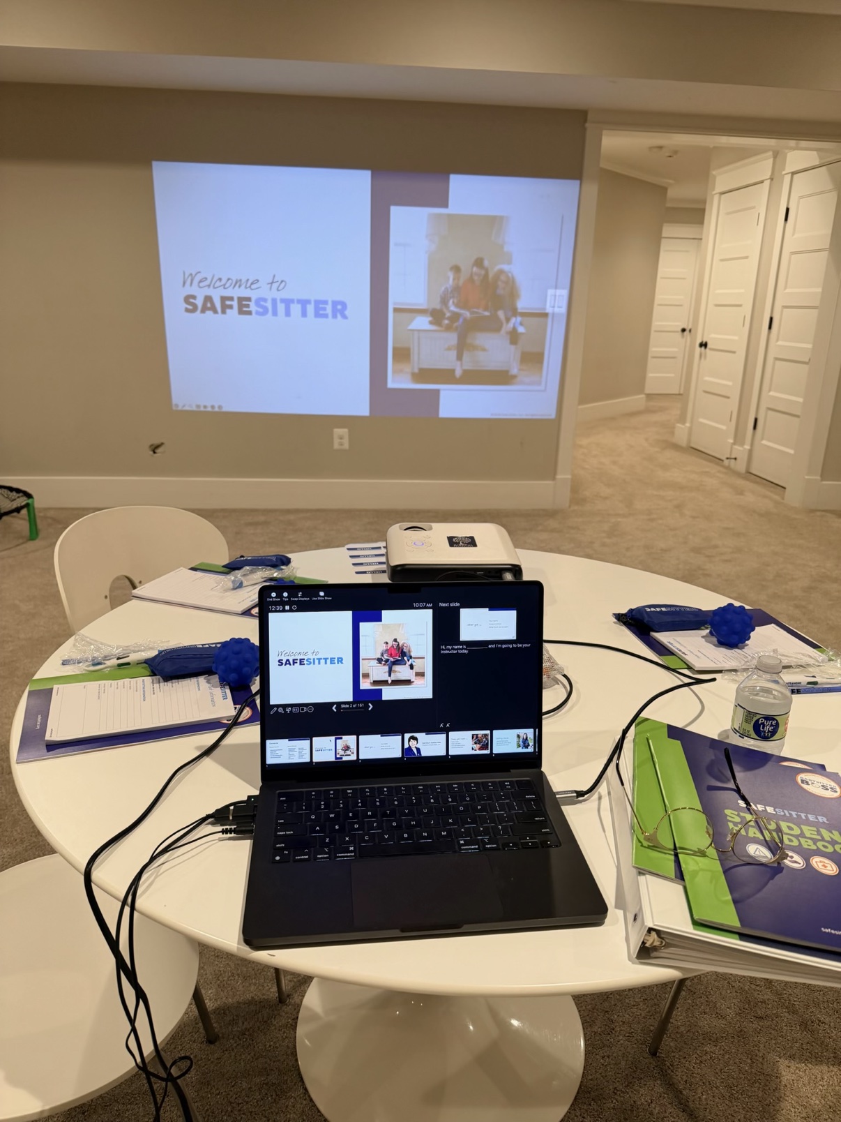 Safe Sitter class setup with projector, laptop and student materials on a table