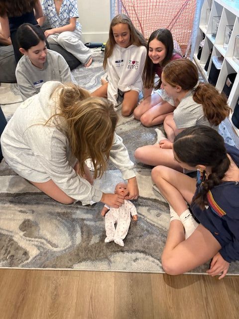 Young students practicing baby care together in class